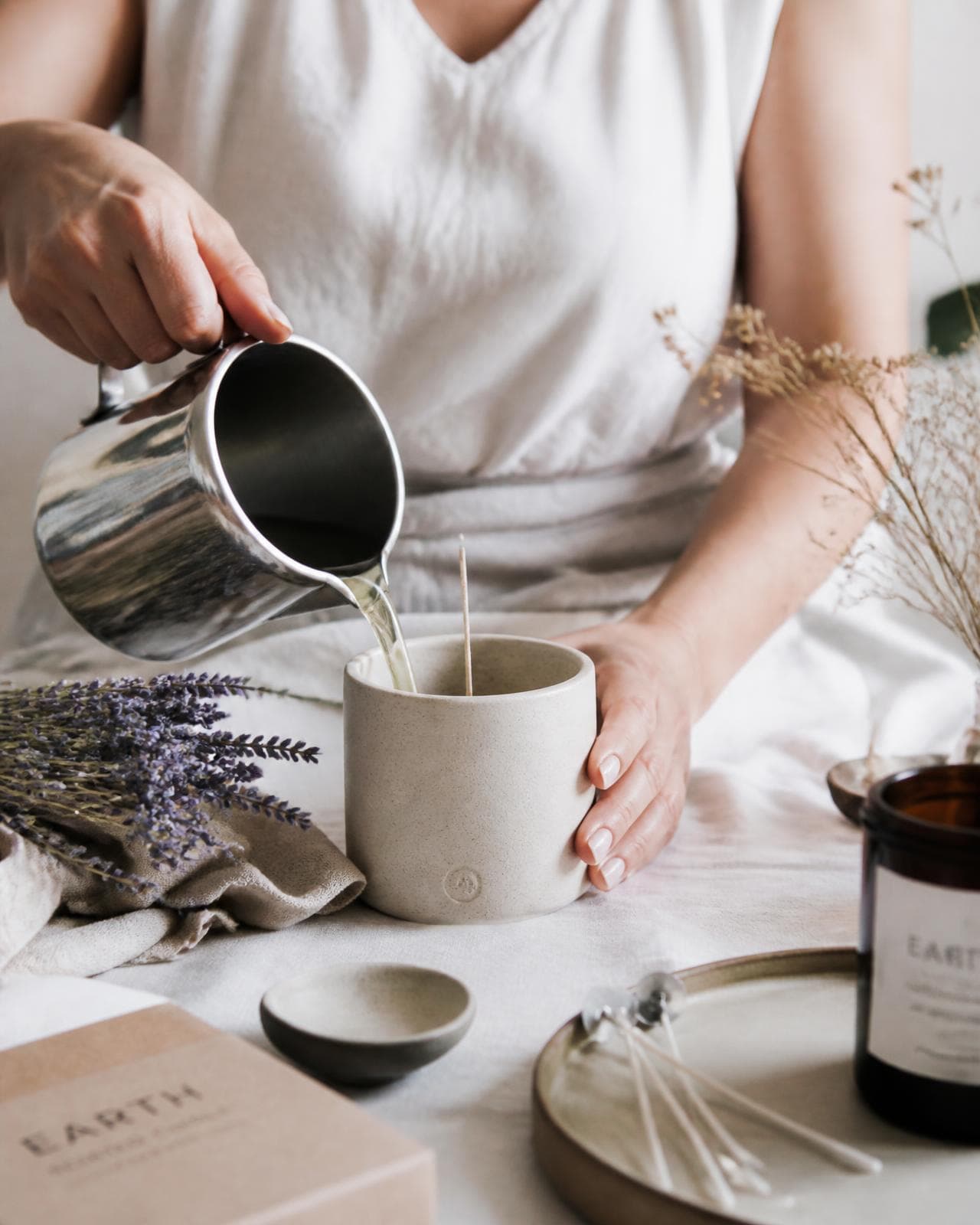 Artesã derramando cera vegetal em recipiente de cerâmica